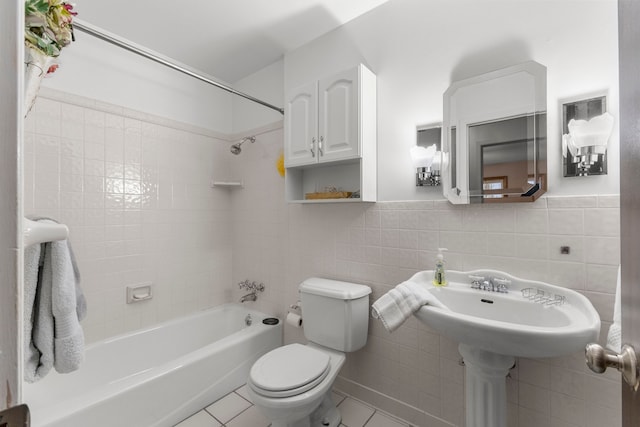 bathroom featuring tile patterned flooring, tiled shower / bath, tile walls, and toilet