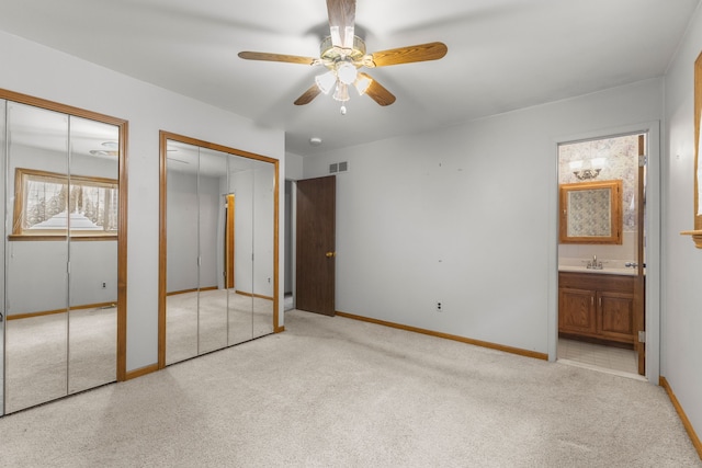 unfurnished bedroom with connected bathroom, sink, two closets, and ceiling fan