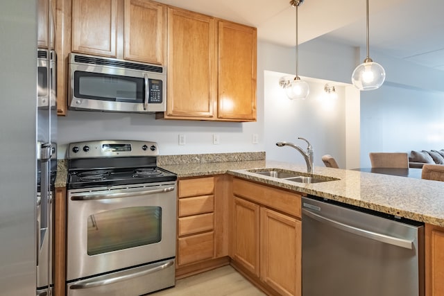 kitchen with sink, appliances with stainless steel finishes, hanging light fixtures, light stone counters, and kitchen peninsula