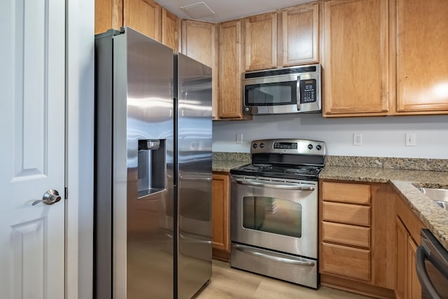 kitchen featuring light stone counters, stainless steel appliances, and light hardwood / wood-style floors