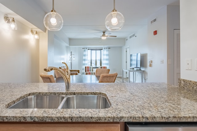 kitchen with decorative light fixtures, dishwasher, sink, light stone counters, and ceiling fan