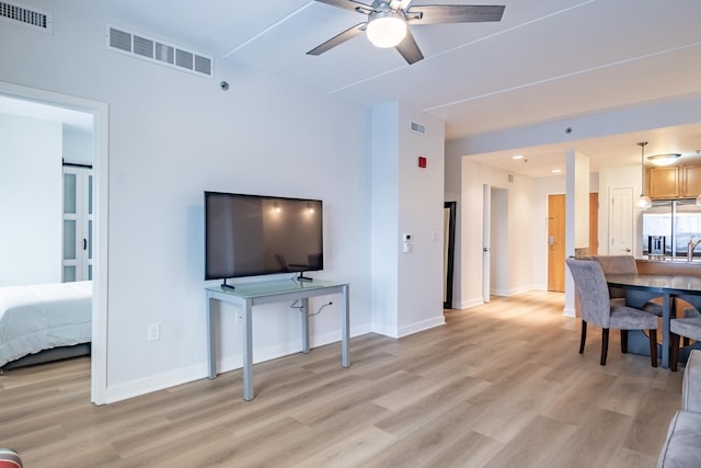 living room featuring sink, ceiling fan, and light wood-type flooring