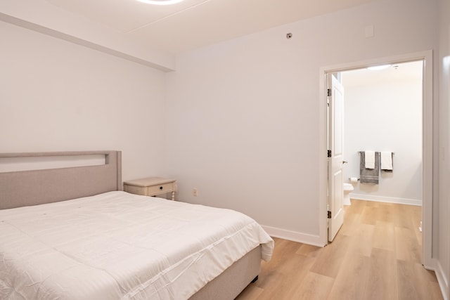 bedroom featuring ensuite bathroom and light wood-type flooring