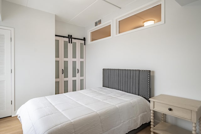 bedroom featuring hardwood / wood-style flooring and a barn door