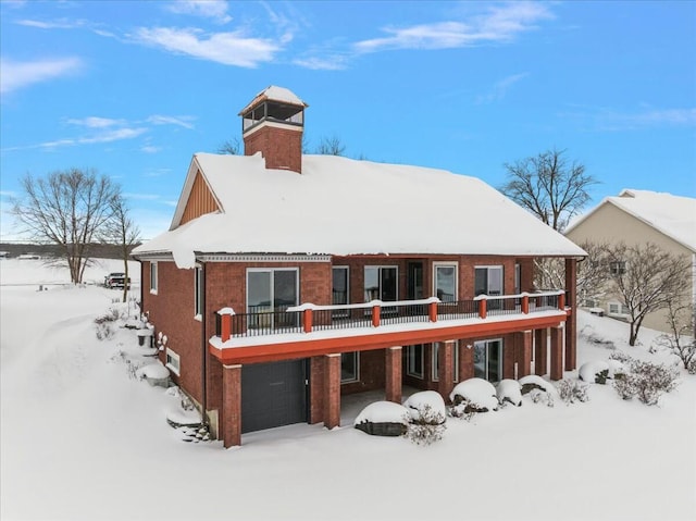 snow covered rear of property with a garage