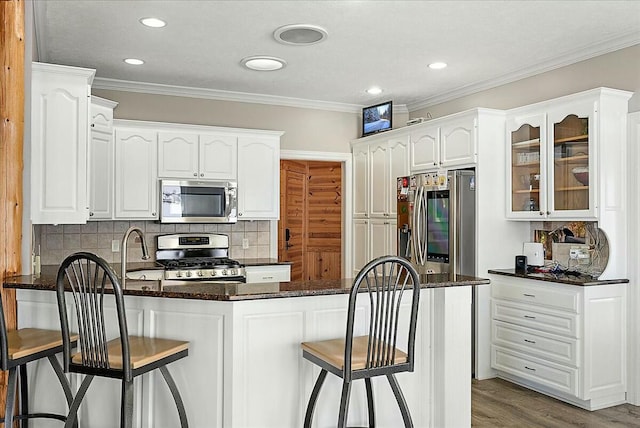 kitchen featuring crown molding, hardwood / wood-style flooring, a breakfast bar, appliances with stainless steel finishes, and white cabinetry