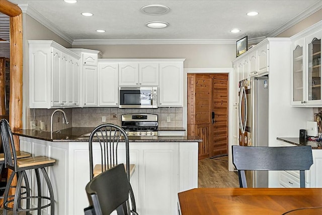 kitchen featuring white cabinetry, backsplash, crown molding, and appliances with stainless steel finishes