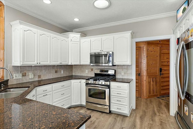 kitchen with sink, appliances with stainless steel finishes, white cabinets, dark stone counters, and backsplash