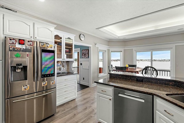 kitchen with white cabinetry, crown molding, dark stone countertops, and appliances with stainless steel finishes