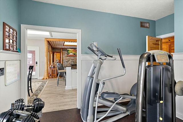 workout room featuring wood-type flooring, a textured ceiling, and wood walls