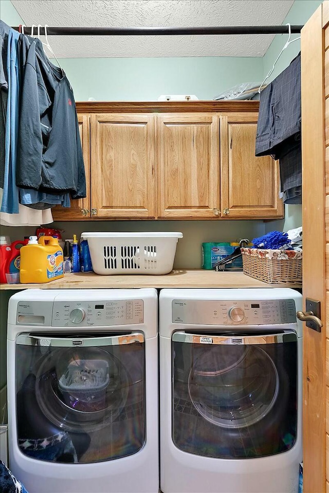 washroom with cabinets, washer and dryer, and a textured ceiling