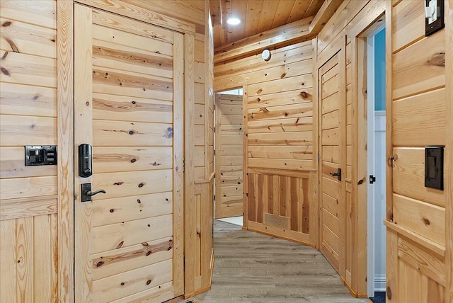 corridor with hardwood / wood-style floors and wood walls