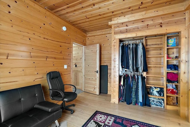 sitting room with wooden walls, wooden ceiling, and light hardwood / wood-style floors