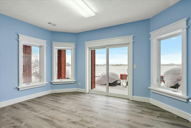 empty room with light hardwood / wood-style flooring, a textured ceiling, and a water view