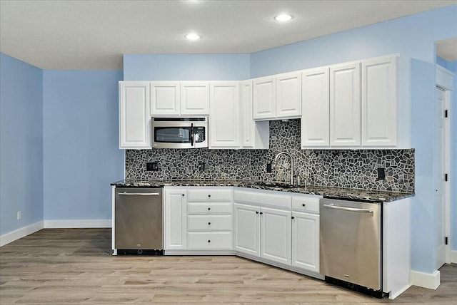 kitchen with white cabinetry, sink, stainless steel appliances, and dark stone countertops