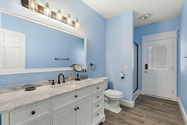 bathroom featuring vanity, toilet, hardwood / wood-style floors, and walk in shower