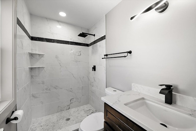 bathroom featuring vanity, toilet, and a tile shower