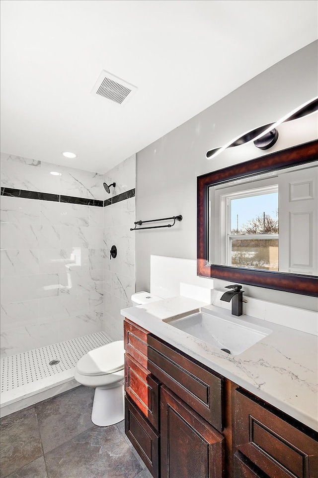 bathroom featuring tiled shower, vanity, and toilet