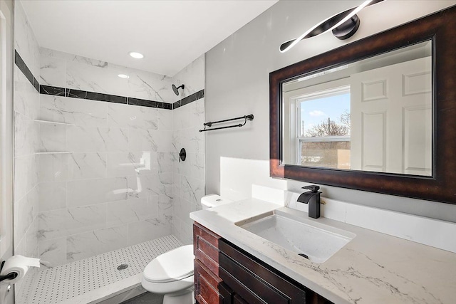 bathroom with vanity, toilet, and a tile shower