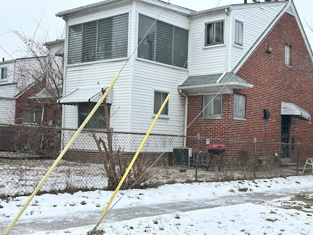 snow covered house featuring cooling unit