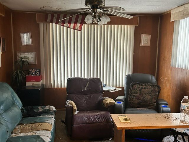 living area featuring wooden walls and ceiling fan