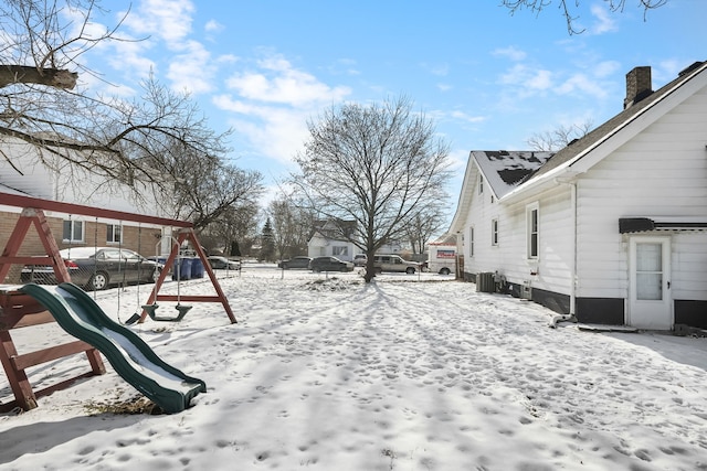 snowy yard with central AC unit and a playground