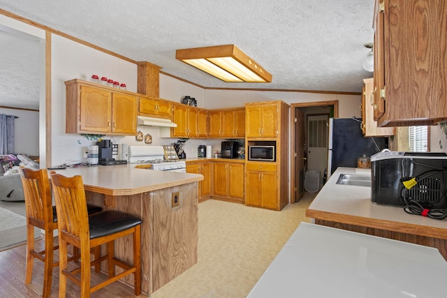 kitchen featuring built in microwave, a kitchen bar, vaulted ceiling, kitchen peninsula, and white gas range oven