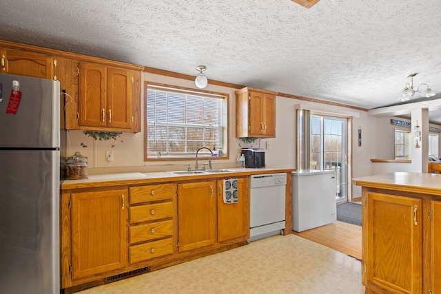 kitchen with dishwasher, sink, stainless steel fridge, crown molding, and a textured ceiling