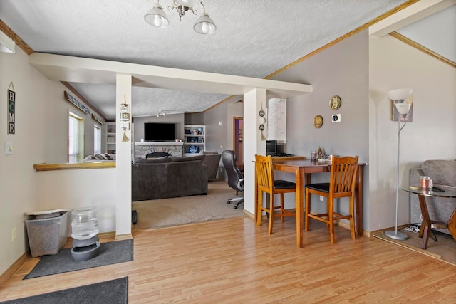 dining room featuring crown molding, lofted ceiling, light hardwood / wood-style floors, and a textured ceiling