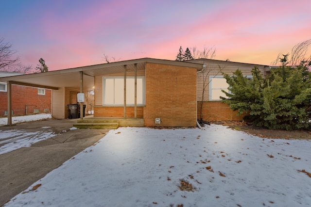 snow covered rear of property featuring a carport