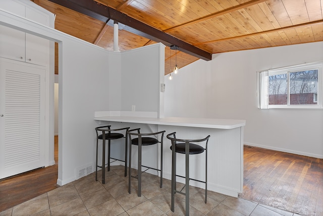 kitchen featuring decorative light fixtures, wooden ceiling, kitchen peninsula, and white cabinets