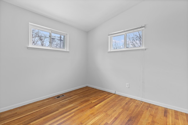 unfurnished room with vaulted ceiling and light wood-type flooring