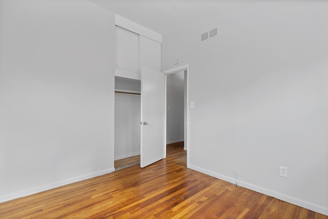 unfurnished bedroom featuring hardwood / wood-style floors and a closet