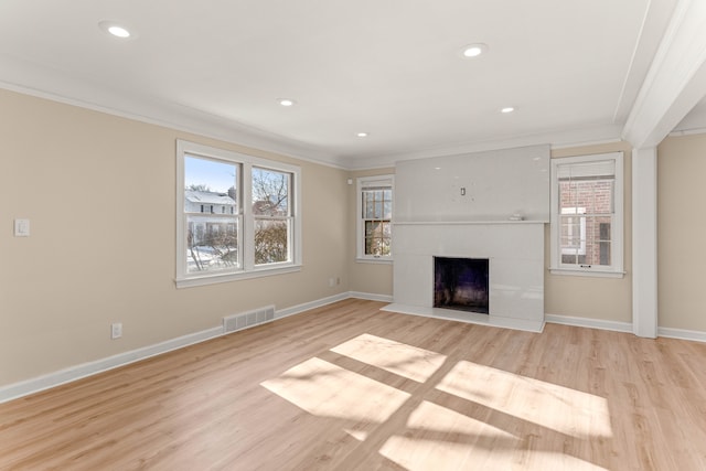 unfurnished living room with light hardwood / wood-style floors, ornamental molding, and a large fireplace