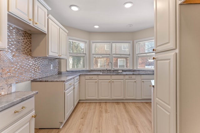 kitchen featuring sink, a wealth of natural light, white cabinets, and light hardwood / wood-style floors