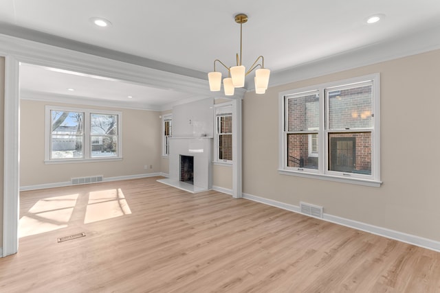 unfurnished living room with crown molding, light hardwood / wood-style flooring, and a notable chandelier