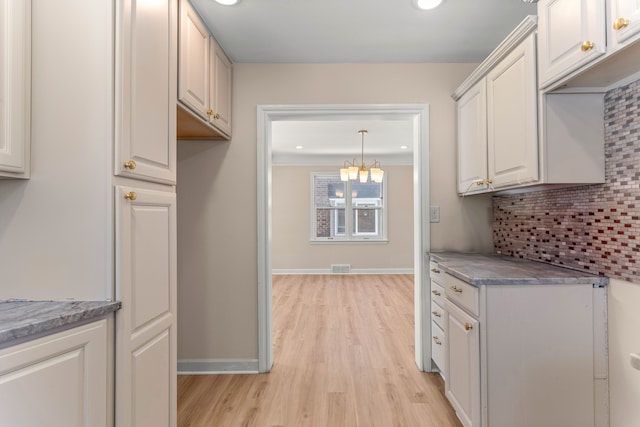 kitchen with light hardwood / wood-style flooring, tasteful backsplash, white cabinets, decorative light fixtures, and a chandelier