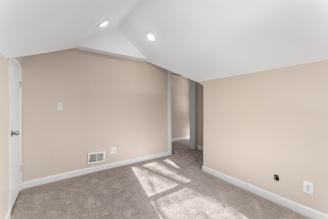 carpeted empty room featuring vaulted ceiling