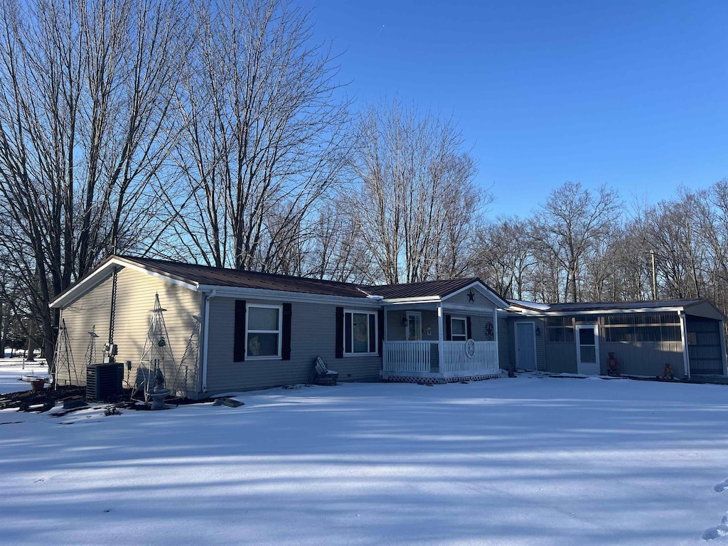 ranch-style house featuring cooling unit, a garage, and a porch