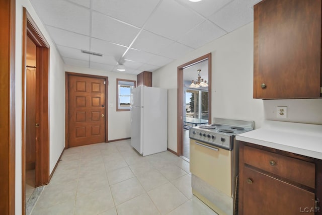 kitchen with white refrigerator, a drop ceiling, and range with electric cooktop