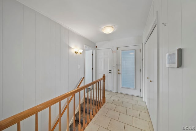 corridor featuring wooden walls and light tile patterned flooring