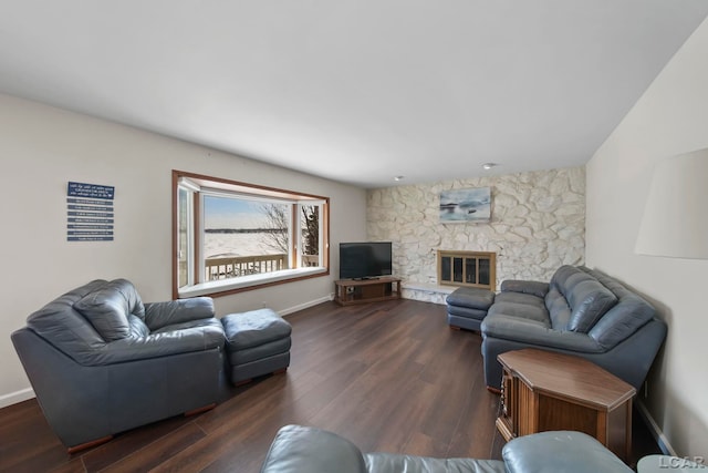 living room with a stone fireplace and dark hardwood / wood-style floors