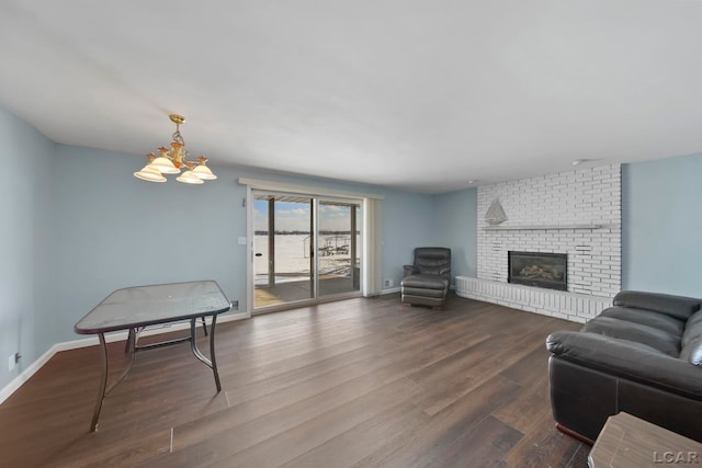 living room with an inviting chandelier, a fireplace, and wood-type flooring