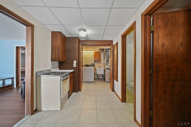 kitchen with washer / dryer, a paneled ceiling, light tile patterned floors, and electric stove