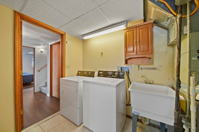 laundry room featuring cabinets, sink, light tile patterned floors, and washer and clothes dryer