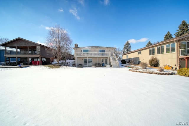 snow covered rear of property with a balcony