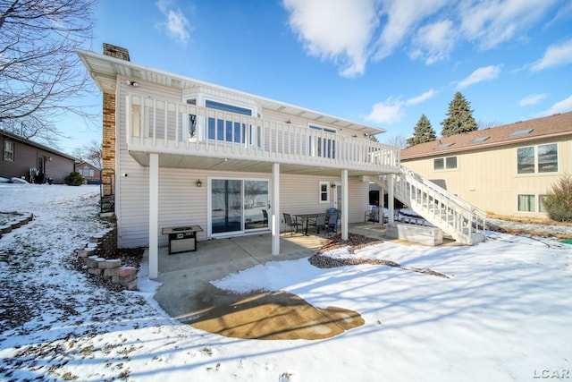 snow covered rear of property featuring a patio