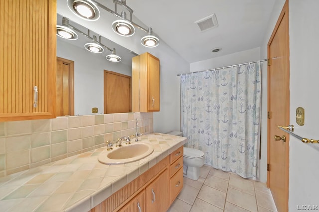 bathroom with decorative backsplash, tile patterned flooring, walk in shower, vanity, and toilet