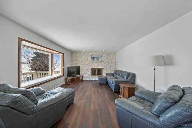 living room with a stone fireplace and dark hardwood / wood-style flooring