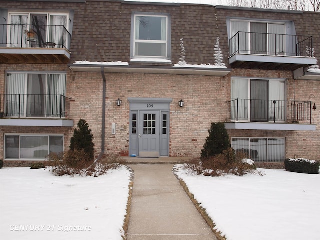 snow covered property entrance featuring a balcony